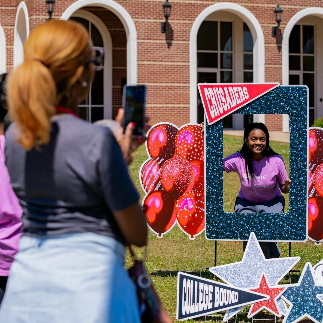 A woman takes a photo at a college campus photo booth.
