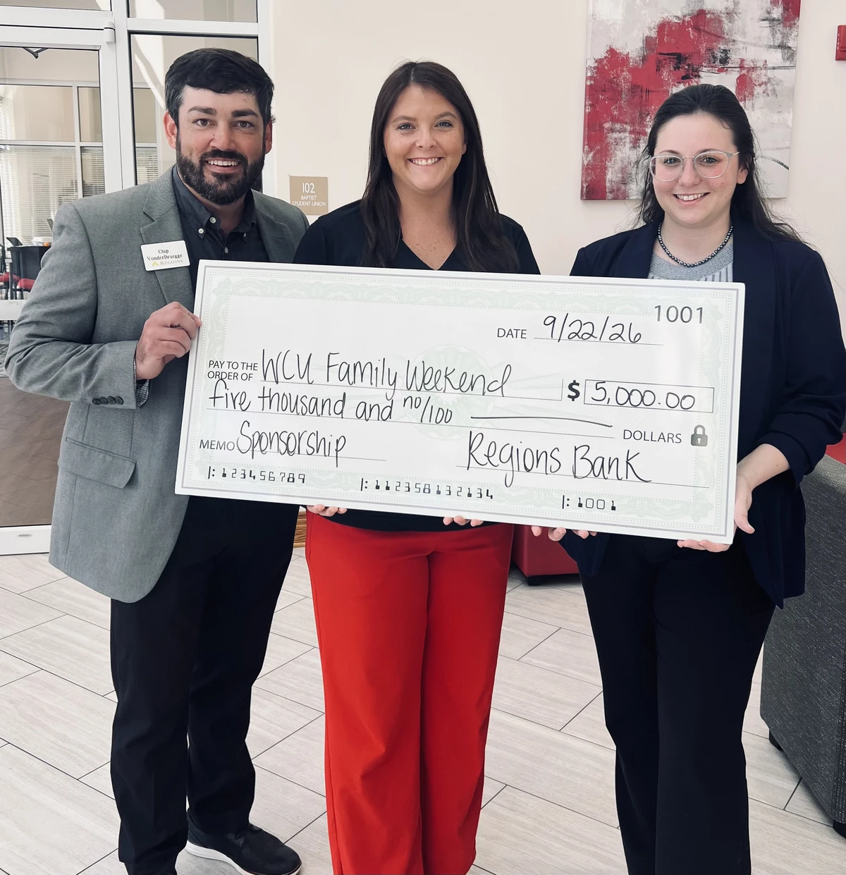 Smiling people holding a large check for a family weekend event.